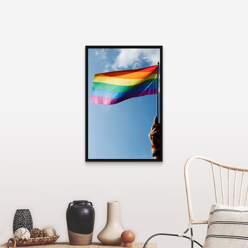 "Person's hand holding rainbow-colored flag waving in the sky" Black Float Frame Canvas Art