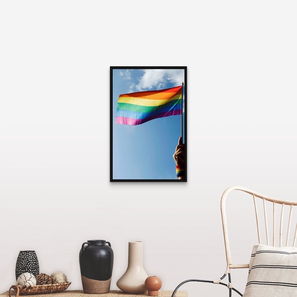 "Person's hand holding rainbow-colored flag waving in the sky" Black Float Frame Canvas Art