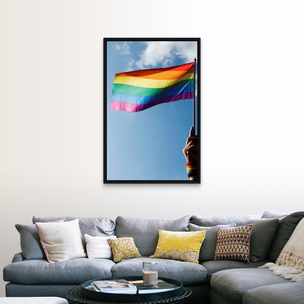 "Person's hand holding rainbow-colored flag waving in the sky" Black Float Frame Canvas Art