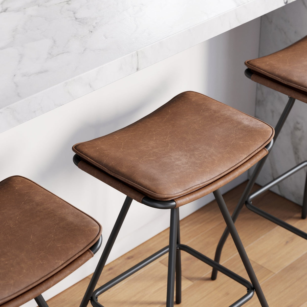 Nathan James Dominique Industrial Backless Kitchen Bar Stool with Brown Leather Saddle Seat and Metal Base